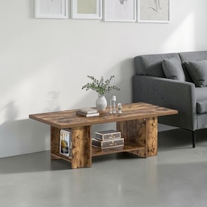 May include: A rectangular coffee table with a rustic brown wood grain finish, featuring a flat top surface and a lower storage shelf. The table is constructed with thick side panels and holds a white vase with greenery, books, and two small boxes.