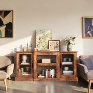 May include: A rustic wooden sideboard featuring two glass-paneled side cabinets and an open central shelving unit. The shelves contain various books, a small rectangular box, and decorative items. The unit has a warm brown wood grain finish.