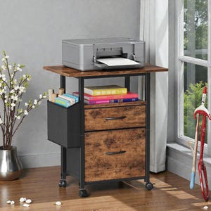 May include: A rolling printer stand with a dark wood-tone top and two drawers with black handles. A gray printer sits on top, with a black fabric organizer on the side. The stand has a black metal frame and is on wheels.