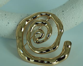Guldfärgad spiralbrosch med statementmotiv