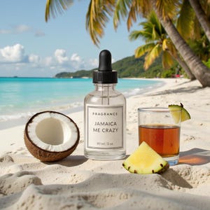 Könnte beinhalten: Eine klare Glas-Duftflasche mit schwarzem Tropfverschluss, beschriftet mit "FRAGRANCE JAMAICA ME CRAZY 60 ml / 2 oz", steht auf einem Sandstrand. Eine halbierte Kokosnuss, ein Cocktail und Ananasscheiben ergänzen die tropische Szene.