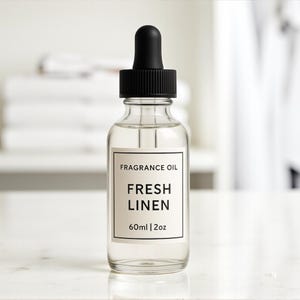 Może przedstawiać: Przezroczysta szklana butelka olejku zapachowego z czarną pipetą. Etykieta głosi "FRAGRANCE OIL FRESH LINEN 60ml | 2oz". Butelka zawiera przezroczysty płyn. Tło jest rozmyte, z białymi i jasnymi kolorami.