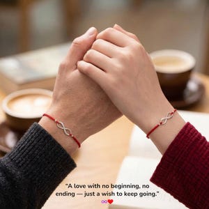 May include: A pair of matching red string bracelets featuring a silver-toned infinity symbol charm. The text "A love with no beginning, no ending — just a wish to keep going." is printed below the bracelets, accompanied by an infinity and heart icon.