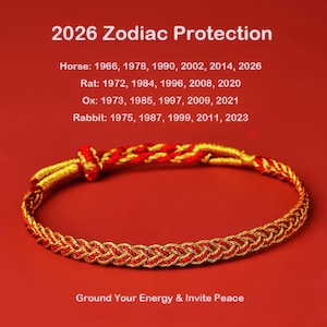 Puede incluir: Una pulsera trenzada roja y dorada con cierre de nudo. La imagen incluye el texto "2026 Zodiac Protection" y enumera los años de nacimiento de los signos del zodiaco Caballo, Rata, Buey y Conejo. También está presente el texto "Ground Your Energy & Invite Peace".
