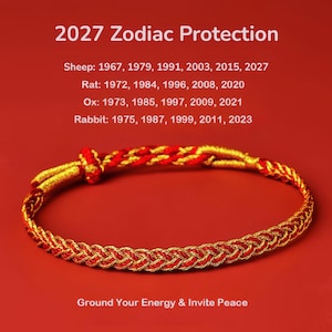 May include: A braided bracelet made of red and gold cord. Above the bracelet, text reads 2027 Zodiac Protection, followed by lists of years for Sheep, Rat, Ox, and Rabbit. Below the bracelet, the text reads Ground Your Energy & Invite Peace.