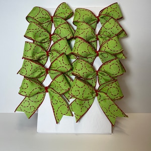 May include: A set of ten green and red bows with a swirl pattern. The bows are made of fabric and have a wired edge.