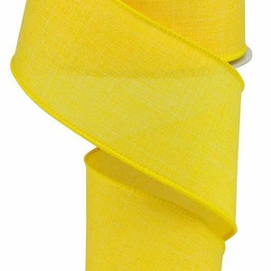 Peut inclure: Une bobine de ruban jaune vif avec un tissage texturé. Le ruban est enroulé autour d'un noyau en carton blanc, avec une partie déroulée et tombant vers le bas. Les bords du ruban sont soigneusement finis, et la couleur est uniforme.