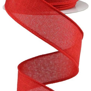 May include: A spool of bright red ribbon with a woven texture. The ribbon is unwound, showing a flowing, curved shape. The spool is white, and the ribbon is a solid, vibrant red.