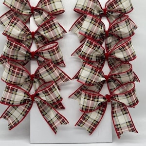 Peut inclure: Dix nœuds en tartan rouge et blanc avec une bordure rouge. Les nœuds sont disposés en deux rangées de cinq sur un fond blanc.