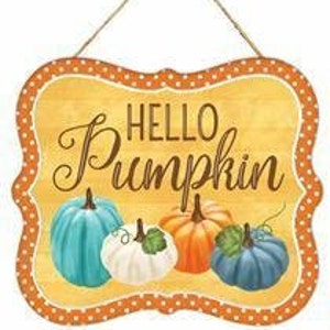 Puede incluir: Un letrero de madera con un borde de lunares naranja y blanco. El letrero dice "Hello Pumpkin" en letras marrones. Hay cuatro calabazas en el letrero: una azul, una blanca, una naranja y una azul.