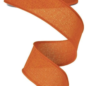 May include: A roll of 2.5 inch wide orange burlap ribbon. The ribbon is woven with a textured pattern and has a slightly frayed edge.