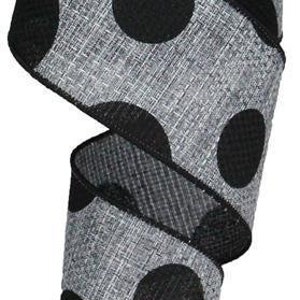 May include: A roll of decorative ribbon featuring a gray fabric with large black polka dots. The ribbon is rolled up on a white spool. The ribbon is suitable for crafts, gift wrapping, and decorations.