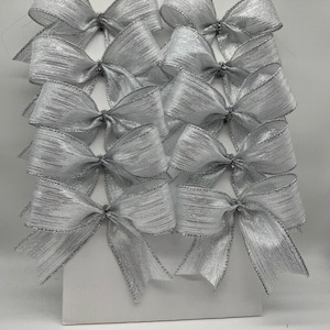 May include: A set of twelve silver shimmer bows, perfect for adding a touch of elegance to gifts, crafts, or home decor.