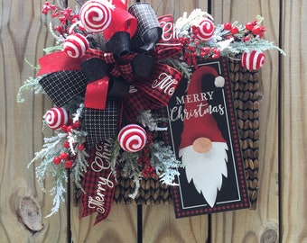 May include: A Christmas wreath with a red and black plaid bow, red and white candy cane ornaments, and a sign that says "Merry Christmas" with a gnome illustration.