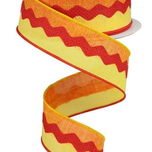 Könnte beinhalten: Gelb-rotes Chevron-Musterband mit strukturiertem, gewebtem Stoff. Das Band befindet sich auf einer weißen Spule.