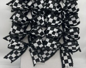 May include: A collection of ten fabric bows arranged in two vertical columns on a white rectangular display card. Each bow features a black and white checkered pattern with frayed, glittery black edges and a central knot detail.
