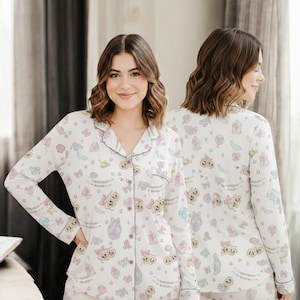 A woman wearing a white pajama top with a pattern of cartoon characters poses for a photo.