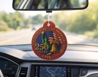 Puede incluir: Un ambientador de coche rojo y circular con un diseño patriótico. Presenta el texto "United States of America" y "250 Years 1776-2026", junto con imágenes de la Estatua de la Libertad, una bandera estadounidense ondeando y la Campana de la Libertad.