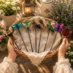May include: A collection of eight stained glass insect garden stakes featuring a bee, dragonfly, moth, ant, wasp, praying mantis, butterfly, and ladybug. Each insect is crafted with colorful glass segments and black metal wire outlines.