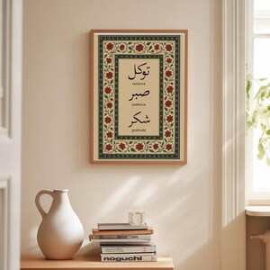 May include: A framed art print with Arabic calligraphy and English translations. The artwork features a beige background with a floral border in red and green. The text includes the words "reliance", "patience", and "gratitude".