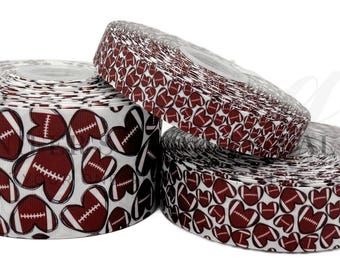 May include: White ribbon with a repeating pattern of brown footballs in heart shapes. The ribbon is rolled up and displayed in three different sizes.