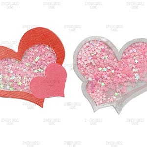 May include: Two heart-shaped decorations. One is red with a clear center filled with pink star-shaped confetti. The other is a pink heart with a clear border, also filled with pink star confetti. A small pink heart is also present.