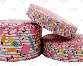 Puede incluir: Tres rollos de cinta rosa y blanca con un diseño escolar. El diseño incluye manzanas, lápices, libros y reglas. La cinta es ideal para manualidades y envolver regalos.