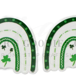 May include: Two white and green rainbow-shaped embellishments. Each has a green dotted border, green shamrock and clover details. The rainbows have a white background with green accents, perfect for St. Patrick's Day crafts.