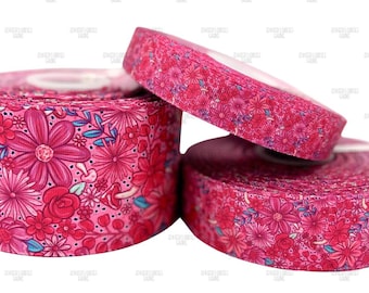 May include: Three rolls of pink floral ribbon. The ribbon features a repeating pattern of pink and red flowers with blue accents. The rolls are stacked, with one partially unrolled.