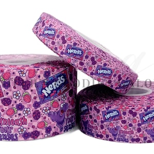 May include: Three rolls of pink Nerds-themed ribbon. The ribbon features a repeating pattern of Nerds candy boxes, strawberries, flowers, and a purple cartoon character. The text "Unleash Your Senses" is also visible.