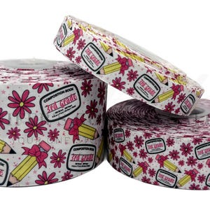May include: Three spools of white ribbon with a pink and yellow print. The ribbon features a pencil with a pink bow, pink flowers, and the text "Composition Book 3rd Grade".