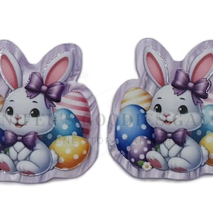 May include: Two Easter-themed decorations shaped like bunnies. Each bunny is white with a purple bow tie and bow. Colorful Easter eggs in blue, purple, and yellow with polka dots and stripes are behind the bunnies. The background is a light purple.