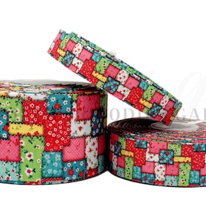 May include: Three rolls of decorative ribbon with a patchwork design. The ribbon features a pattern of small squares in various colors, including pink, red, green, and blue, with floral and geometric motifs. The rolls are of different sizes.