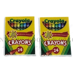 May include: Two rectangular boxes of Crayola crayons, each containing 24 wax sticks. The packaging is yellow with green accents, featuring the Crayola logo, the text "Preferred by Teachers!", and a red circular graphic displaying the number 24.