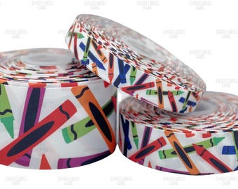 Puede incluir: Tres rollos de cinta blanca decorados con un colorido patrón de crayones. Los crayones son en tonos de rojo, naranja, verde, morado y azul. La cinta se utiliza probablemente para manualidades o envolver regalos.