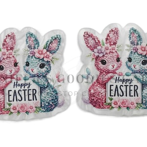 May include: Two Easter bunny decorations, one pink and one teal, holding a sign that says "Happy Easter." The bunnies are decorated with sequins and flowers. The decorations are on a white background.