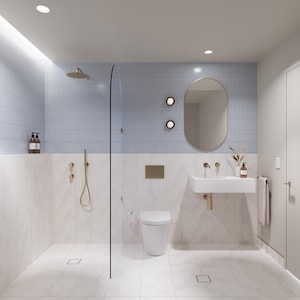 May include: A modern bathroom with a light blue tiled wall and white marble-look tile. Features include a glass shower enclosure, a wall-mounted sink with a gold faucet, and a round mirror. The room is well-lit with recessed lighting.