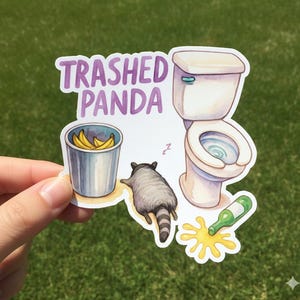 May include: A sticker with the text "Trashed Panda" above an illustration of a raccoon, a toilet, a trash can with bananas, and a spilled bottle. The raccoon is lying down next to the toilet.