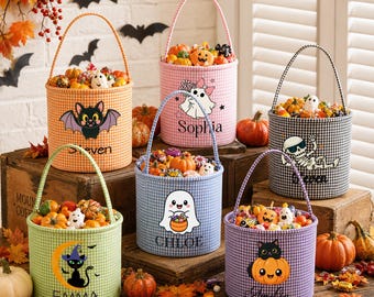 Może przedstawiać: Sześć cylindrycznych, materiałowych wiader na słodycze na Halloween w kratkę vichy w kolorach pomarańczowym, różowym, czarnym, zielonym, niebieskim i fioletowym. Każde wiadro ma unikalną grafikę postaci, uchwyt i nadrukowane imię z przodu.
