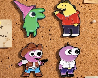 Pode incluir: Quatro pinos de esmalte coloridos com personagens de desenhos animados. Um é verde com um chapéu rosa, outro é amarelo com um capuz vermelho, um terceiro é rosa com um chapéu de cowboy e o último é roxo com uma camisa branca.