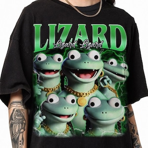May include: Black t-shirt featuring a graphic of four cartoon lizards with gold chains and earrings. The word "LIZARD" is printed in large green letters above the lizards, with "Lizard Lizard" in smaller letters below.