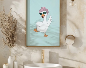 May include: Framed art print featuring a cartoon goose wearing sunglasses and pink curlers. The goose is depicted in a playful pose against a light blue background. The artwork is framed in a gold-colored frame and is displayed in a bathroom setting.