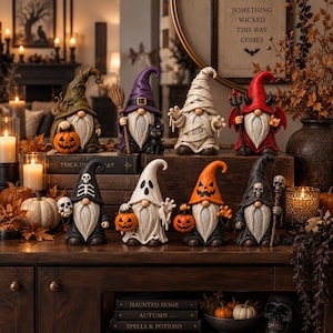May include: Eight decorative gnome figurines arranged on wooden surfaces. The gnomes feature various Halloween-themed costumes including a witch, mummy, devil, ghost, and skeleton designs, holding accessories like pumpkins, a broom, and skulls.
