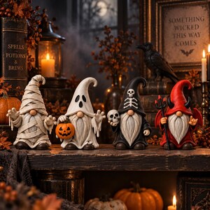 May include: Four decorative gnomes featuring Halloween themes: a mummy wrapped in bandages, a ghost holding a pumpkin, a skeleton figure holding a skull, and a red devil with horns and a pitchfork. Each gnome has a long white beard.