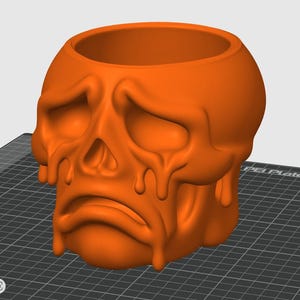 May include: Orange skull-shaped planter with a sad expression and dripping effect. The planter has a large opening at the top for plants or other items. The design is a unique and spooky decorative piece.