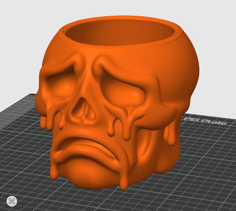 May include: Orange skull-shaped planter with a sad expression and dripping effect. The planter has a large opening at the top for plants or other items. The design is a unique and spooky decorative piece.