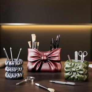 May include: A collection of decorative desk organizers in the shape of bows. The organizers are in shades of blue, burgundy, and green. A magnifying glass, pens, and writing utensils are also on the wooden desk. The logo for 3D Salt Lab is in the bottom corner.