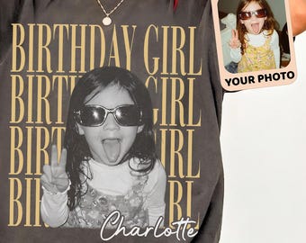 Puede incluir: Una camiseta gris carbón con el texto BIRTHDAY GIRL repetido en una fuente serif color canela. El centro muestra la imagen de un niño con gafas de sol sacando la lengua, con el nombre Charlotte escrito debajo en letra cursiva blanca.