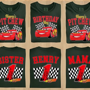 Pu&ograve; includere: T-shirt verde scuro con vari disegni raffiguranti un'auto da corsa rossa, bandiere a scacchi e testo. I disegni includono "Henry's Pit Crew", "Birthday Boy", "Sister", "Henry" e "Mama". &Egrave; presente anche il numero "95".