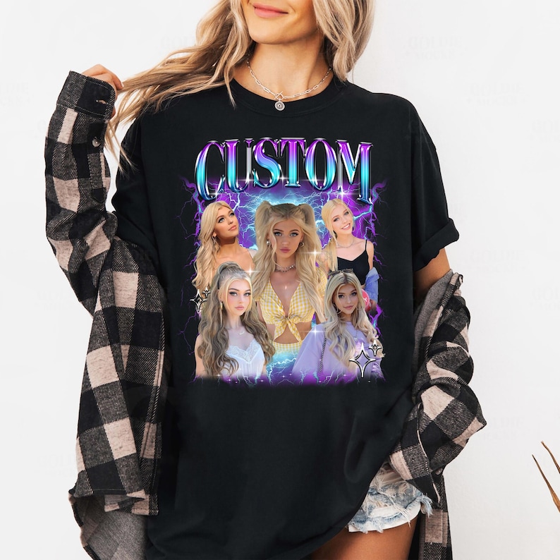 May include: Black long-sleeved t-shirt with a graphic design featuring the word "CUSTOM" in a stylized font. The design includes images of a person with blonde hair, set against a backdrop of purple and blue lightning bolts. The shirt is worn by a person.